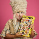 Person in historical costume holding a 'LE PUZZ' puzzle against a pink background