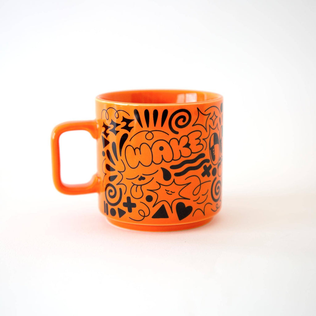 Orange mug with black abstract designs and 'Wake up' text on a white background