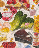 Jigsaw puzzle with food-themed pieces including a slice of cake, salad, and candies.