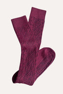 Pair of burgundy socks on a light pink background